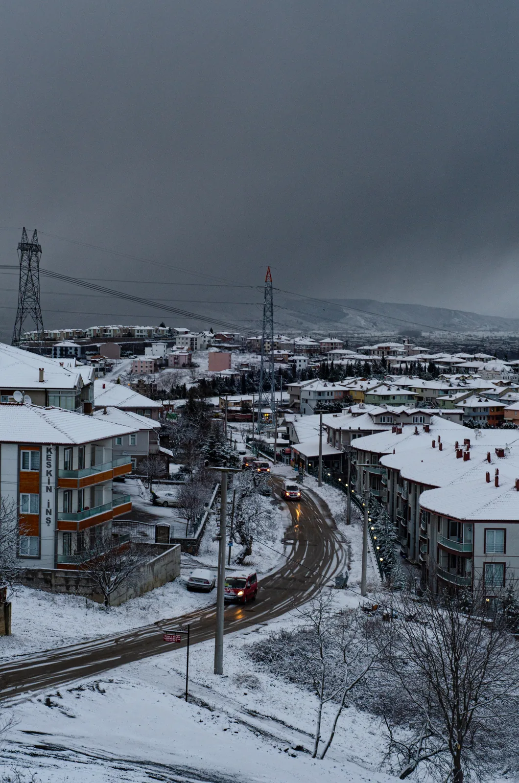 Karla kaplı çatılar ve aralarında kıvrılan bir yol